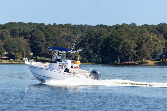 Fishermen on center console fishing boat enjoy summer day on the lake. Power boat cruising on freshwater lake.