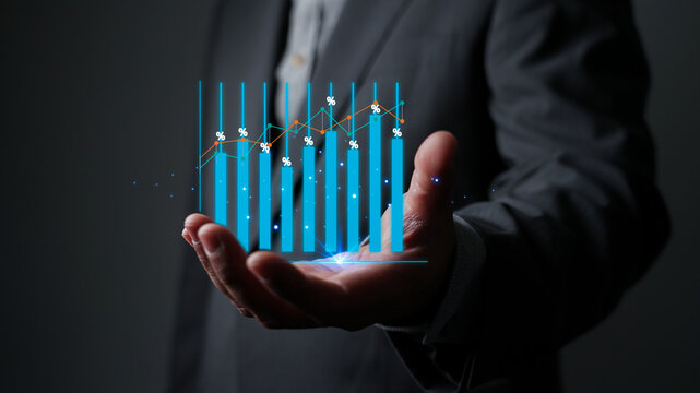 Businessman holding a holographic virtual bar chart with a growing stock market graph. Concept of business growth, financial investment, and technology for success and future analysis.
