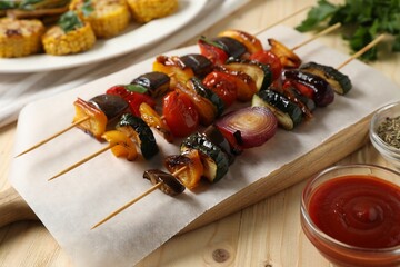 Skewers with tasty grilled vegetables served on wooden table, closeup