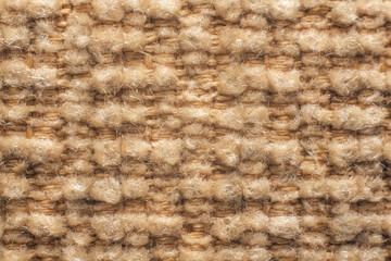 Close-up macro texture of beige woven fabric with soft fibers and warm natural surface background