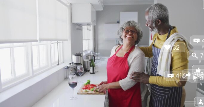 Slicing tomatoes, senior woman and man cooking in home kitchen, with cutting board and wine glass - Powered by Adobe