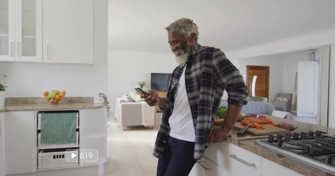 Leaning man wearing plaid shirt checking smartphone in modern kitchen, with carrots, copy space - Powered by Adobe