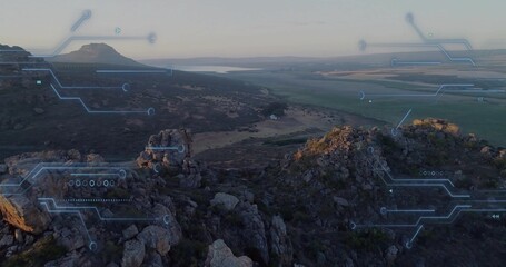 Showing aerial jagged outcrop with scrub plants on plateau, with distant reservoir and HUD overlay