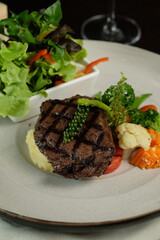 A beautifully presented gourmet meal, featuring a grilled steak and fresh salad