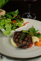 A beautifully plated grilled steak dish with vegetables and wine, ideal for a fine dining experience