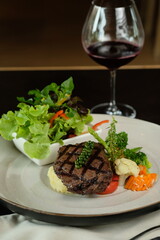 Gourmet steak dish with side of fresh salad and wine glass, a delicious meal ready to be enjoyed