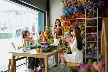 Diverse group of young people arranging flowers in florists workshop while attending class on floral art