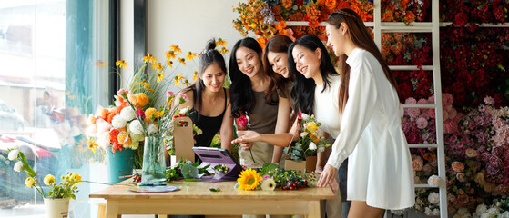 Diverse group of young people arranging flowers in florists workshop while attending class on floral art