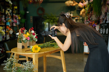 Young asian women owner floral store using digital camera take a photo bouquet sending to client....
