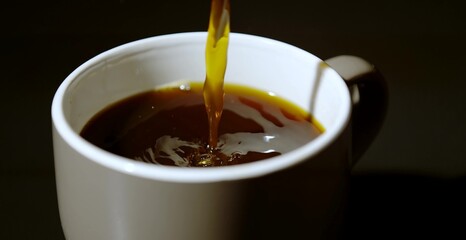 Fresh hot coffee being poured into a white cup, creating ripples on the surface, symbolizing warmth, energy, and a perfect morning moment
