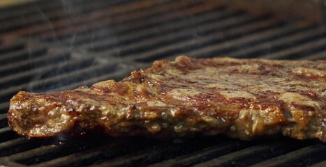 Juicy grilled steak cooking on hot barbecue grill with smoke rising, symbolizing flavor, heat, and delicious barbecue moment perfect for food, restaurant, and cooking themes
