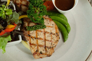 Grilled Pork Chop Meal Garnished with Vegetables and Sauce