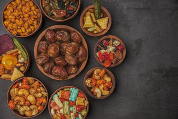 Fototapeta premium Different types of nuts, seeds and dried fruits on black background. Foods with high in vegan protein, vitamins and antioxidants for immune system boosting. Isolated top view with copy space.
