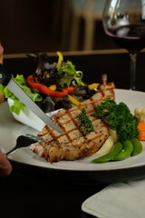 A close-up view of someone slicing through a delicious grilled chicken dish, a fork at hand, ready to savor a delectable meal