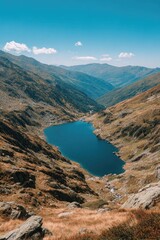 Naklejka premium A mountain lake nestled in a valley, surrounded by peaks and clear blue skies