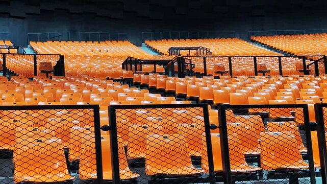 Rows of empty orange plastic seats in a stadium scene. Interior for show, sport event, musical performance and concerts.