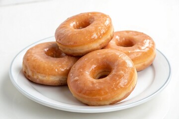 A small stack of glazed donuts resting on a white porcelain plate