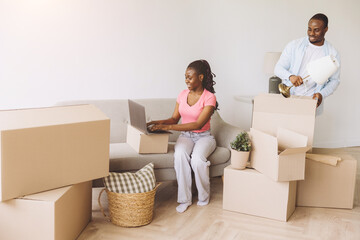 African couple moving into new apartment using laptop