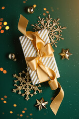 Merry Christmas and Happy Holidays greeting card, frame, banner. New Year. Golden Christmas ornaments and gifts, presents on green background top view. Xmas holiday festive theme. Christmas decoration