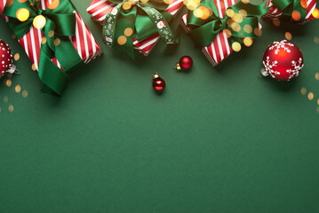 Merry Christmas and Happy Holidays greeting card, frame, banner. New Year. Red Christmas ornaments and gifts, presents on green background top view. Xmas holiday festive theme. Christmas decoration