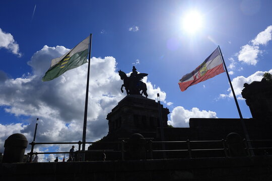 Reiterstandbild Deutschen Eck in Koblenz zwischen Fahnen im Gegenlicht fotografiert