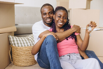 African couple celebrating moving day holding new house keys