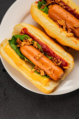 Hotdog fried onions, sausage, bun, sauce fast food tasty snack fresh delicious gourmet food background on the table rustic top view copy space