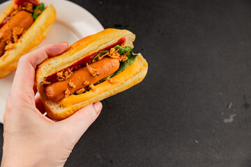 Hotdog fried onions, sausage, bun, sauce fast food tasty snack fresh delicious gourmet food background on the table rustic top view copy space