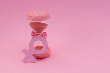 Hourglass with the female gender symbol. Women's health, menopause concept.