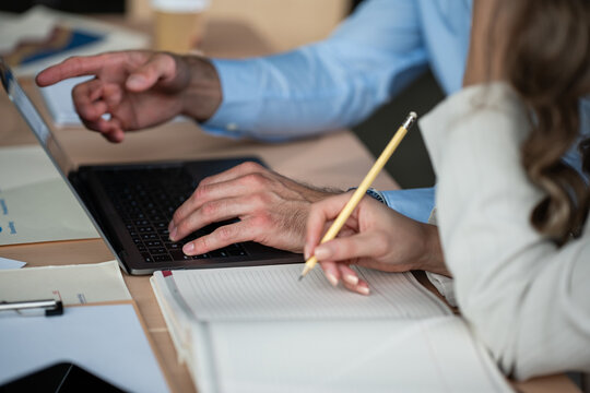 Business colleagues collaborating on laptop and taking notes