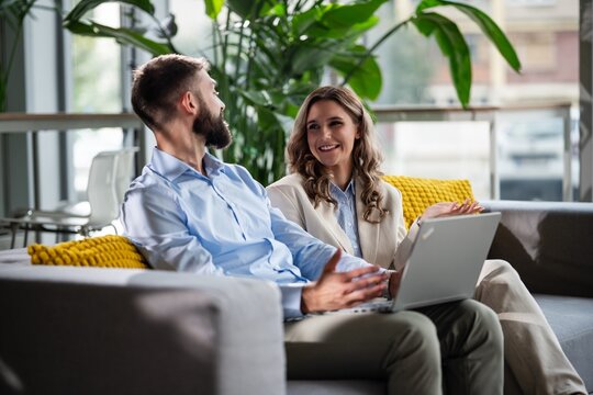 Business colleagues collaborating on laptop in modern office lounge