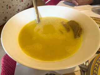 Creamy pumpkin soup in white bowl on dining table