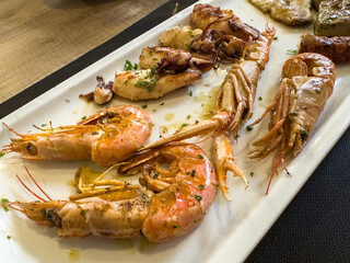 Grilled seafood platter with shrimp, squid, and langoustines on a rectangular plate