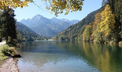 Scenic lake framed by forested hills and mountains, clear blue sky overhead