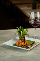 A gourmet dish artfully presented with a glass of red wine. The plate showcases a colorful and delicious culinary creation, inviting viewers to savor the moment