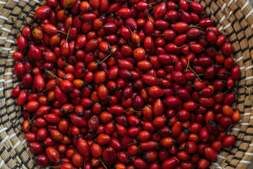 Close-up of red rose hips in woven basket
