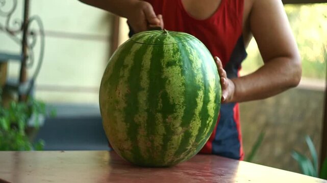 A man is cutting a large watermelon