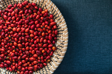 Basket of rose hips on blue fabric background