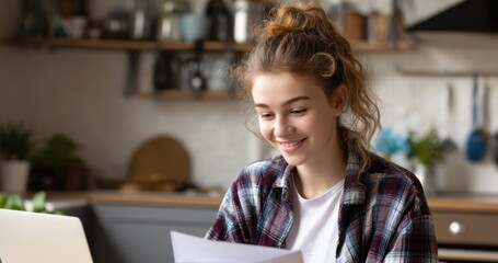 Joyful teen girl using a laptop for her college application at home