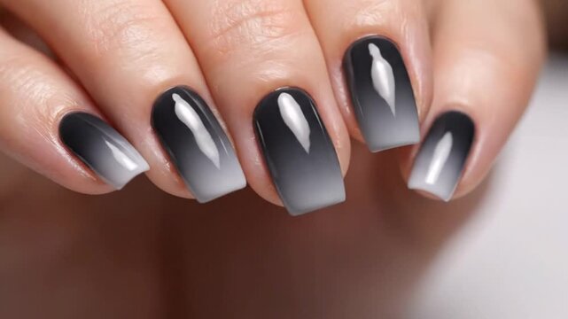 A woman's hand showcasing trendy black and white gradient manicure with a glossy finish.