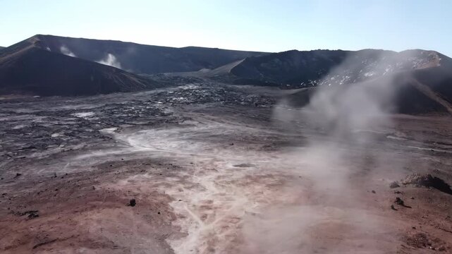 Drone slowly rising from a volcanic landscape, revealing a plume of fine volcanic dust from a fumarole at midday earth's power, geology, barren