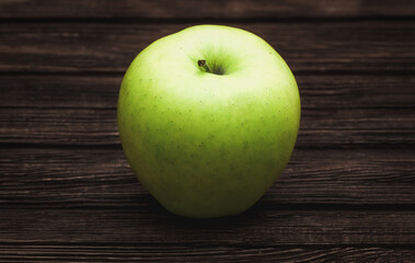 Green apple on dark brown wooden background. Summer fruits. Natural vitamins. Healthy food.