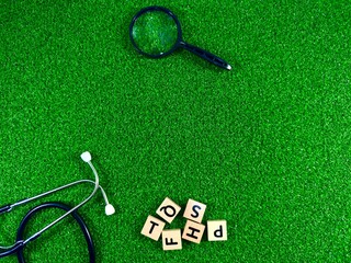 Stethoscope and magnifying glass analyzing medical blocks on grass