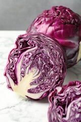 Obraz premium Whole and cut red cabbages on white marble table, closeup