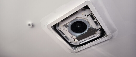 New ceiling fan duct being installed in room ceiling with sheetrock being repaired, Air conditioner...