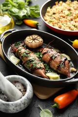Tasty cooked squids with sauce, garlic and products on black table, closeup