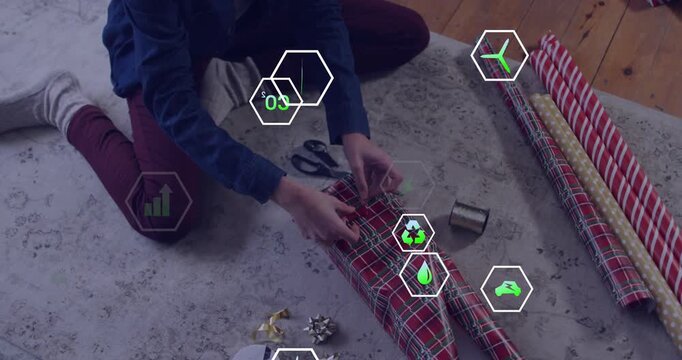 Woman pulling plaid paper trimming edges, folding gift packaging while eco metrics icons overlaying