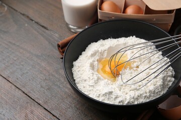 Ingredients for dough and whisk on wooden table, closeup. Space for text