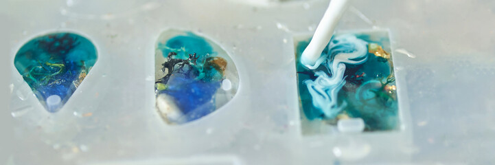 Crafting colorful resin jewelry close-up of blue and white swirls in mold.