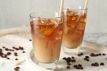 Tasty iced coffee with milk and beans on table